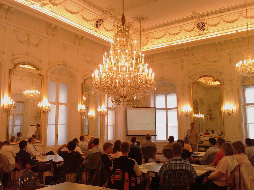zur Vergrößerungsansicht des Bildes: Studierende lauschen einem Vortrag im festlichen Spiegelsaal der Andrássy Universität Budapest.