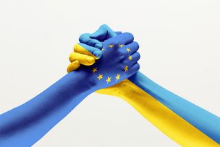 Zu sehen sind zwei Hände in den Farben der EU und der Ukraine, die ineinander greifen.
