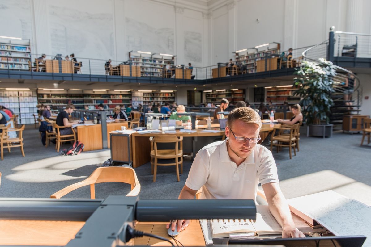 enlarge the image: Mann liest in der Bibliothek