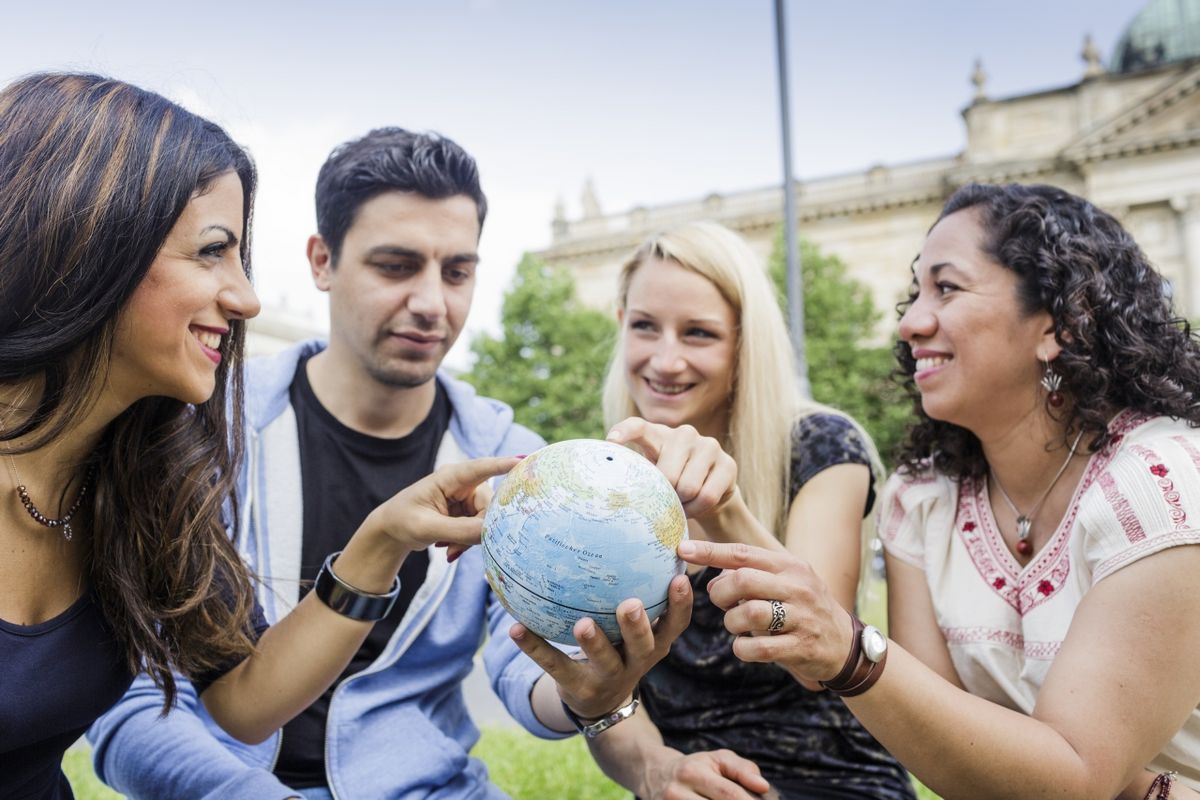 zur Vergrößerungsansicht des Bildes: Internationale Studierende zeigen auf eine Erdkugel