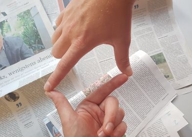 Zwei Hände bilden einen Rahmen über einem Stapel Zeitungen