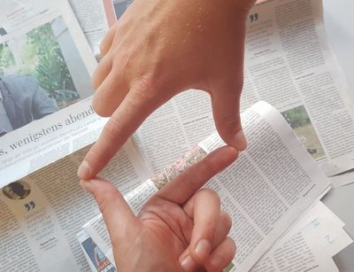 Zwei Hände bilden einen Rahmen mit den Fingern, im Hintergrund liegen Tageszeitungen, Foto: Nina Vogt