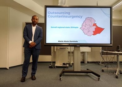 PhD student Abel Abate Demissie during thesis defence. Photo: GESI PhD student stands next to a screen with his presentation for the thesis defense. Photo: GESI