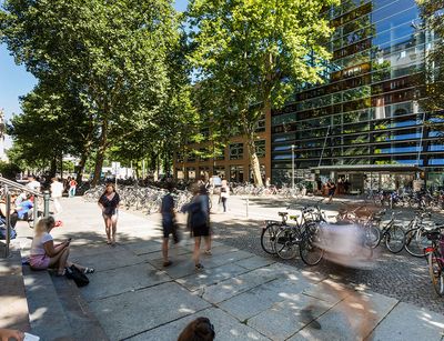 Students in front of the university library. Their outlines are blurred because they are in motion