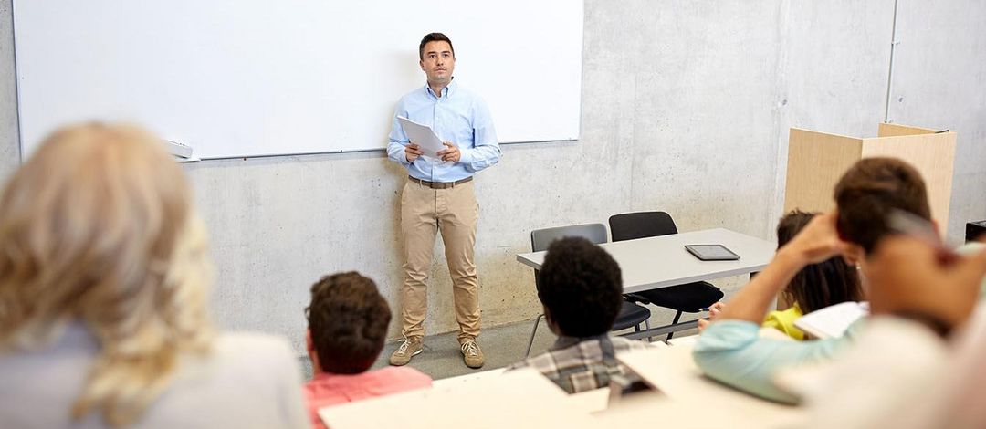 Dozent steht vor einer Gruppe Sturierender im Hörsaal