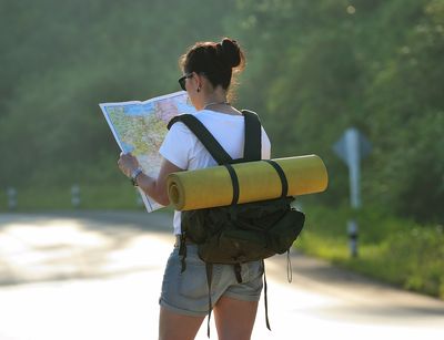 Junge Frau mit Rucksack schaut sich Landkarte an