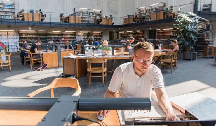Foto: Zu sehen ist die Frontalansicht eines Studierenden im Lesesaal der Bibliotheca Albertina (Universität Leipzig), weitere Studierende sind im Hintergrund.