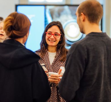 Pre-Doc Award Kick Off 2024 Frau, die eine Tasse hält, unterhält sich lächelnd in einer Gruppe von Menschen