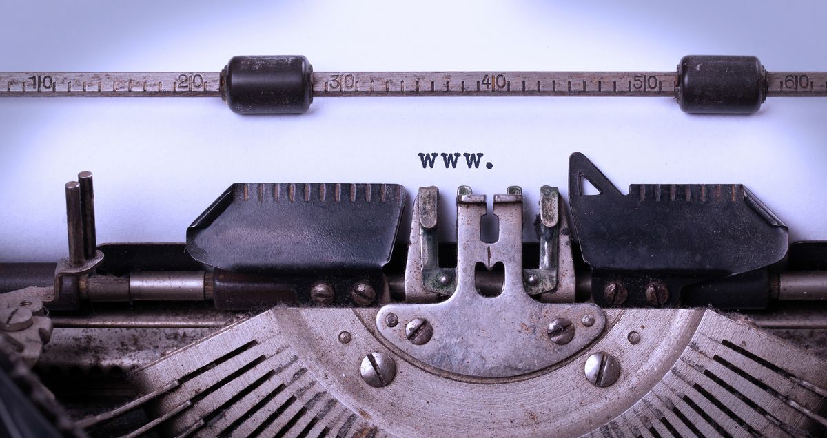 Detaillierte Ansicht der Typenhebel einer alten Schreibmaschine, mit der WWW. auf ein weißes Blatt Papier geschrieben wurde.