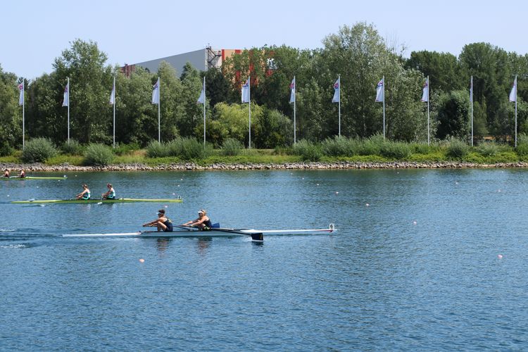 Man sieht ein Zweier-Kanu auf dem Wasser von der Ferne.
