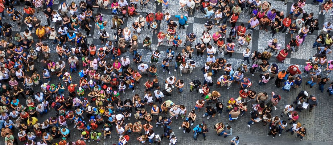 Foto: Blick von oben auf einen mit Menschen befüllten Platz.