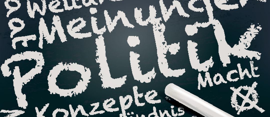 Auf dem Bild sind verschiedene Wörter auf eine Tafel geschrieben, welche mit dem Fach Gemeinschaftskunde zu tun haben. Unter anderem: Politik, Staat, Macht, Weltanschauung, Herrschaft, Meinungen.
