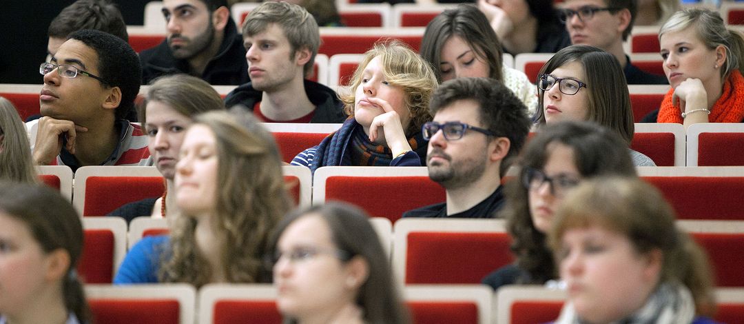 Foto: Studierende sitzen im Hörsaal und hören aufmerksam zu