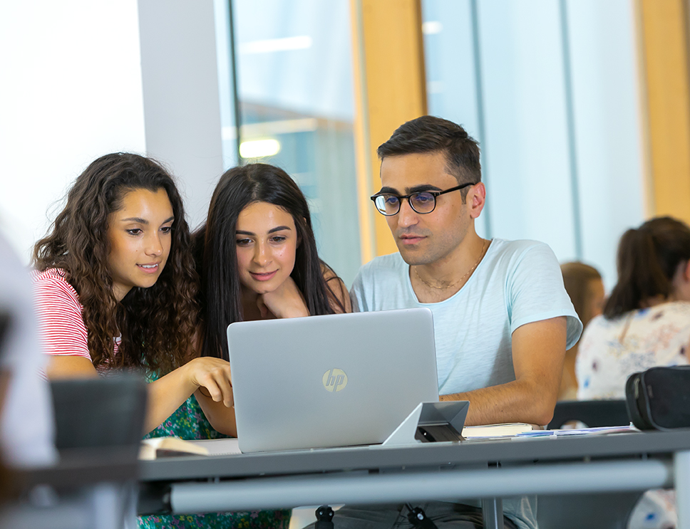 zur Vergrößerungsansicht des Bildes: Symbolbild: Drei Studierende arbeiten gemeinsam an einem Laptop.